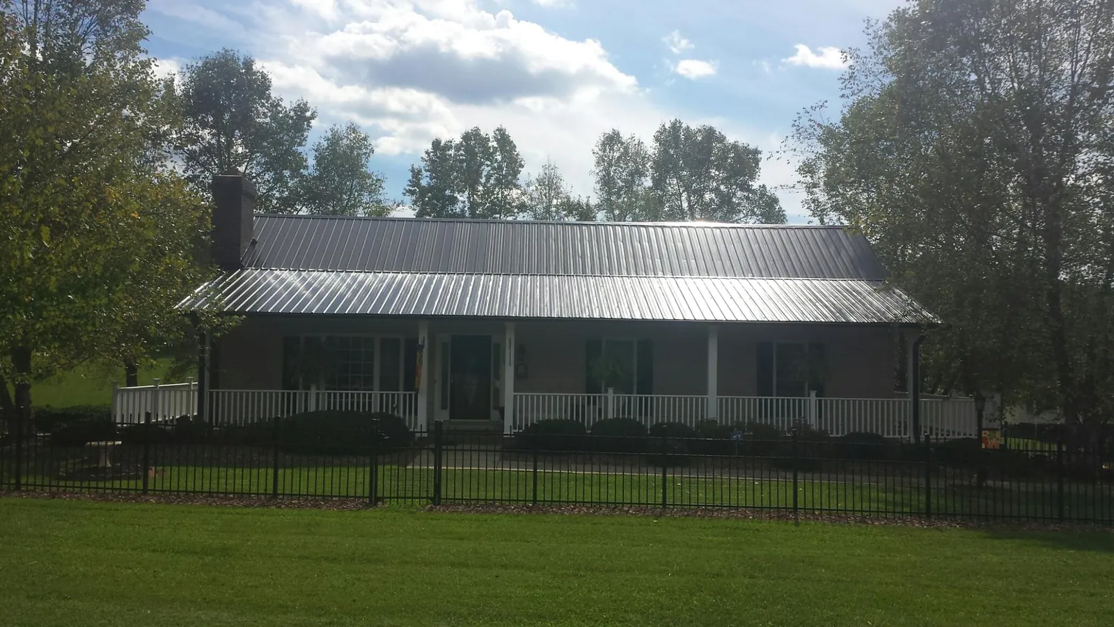 Gray metal roof on a brick ranch with a full width front porch — Gutter Guard Installation work by our crew in Polo