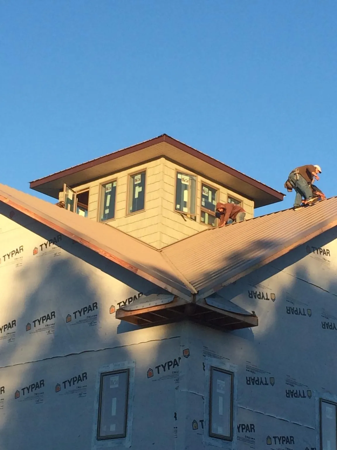Roofers working around a rooftop cupola on a new metal roof at sunset — Roof Waterproofing in Polo by Roofing Brothers